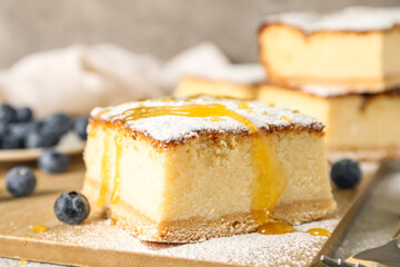 Wooden board with piece of cottage cheese casserole and blueberry on table, closeup