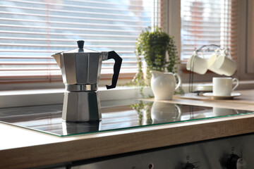 Geyser coffee maker on electric stove in kitchen near window