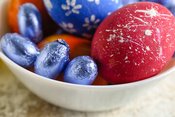 Bowl with painted Easter eggs and candies, closeup