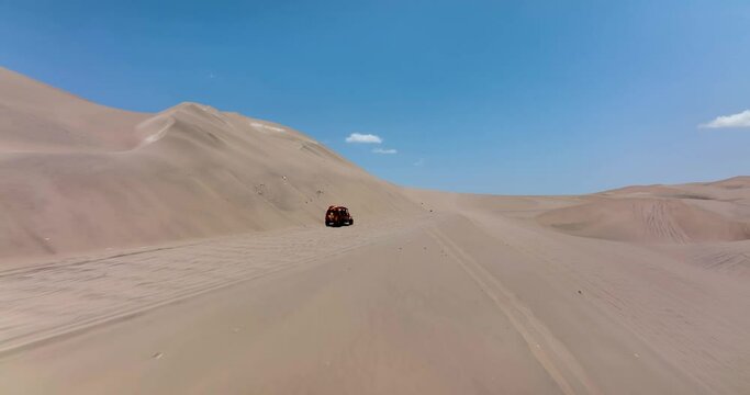 Dune buggies in Huacachina, Peru desert. Fast sand buggy driving on the sand dunes in the desert. Outdoor motorsports activities on a fun sunny day. Aerial above view drone high resolution 4k