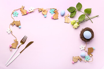 Frame made of Easter bunnies, cutlery and eustoma flowers on lilac background