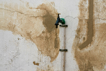 Canilla vieja sobre pared remendada con cemento y pintura vieja - obrazy, fototapety, plakaty