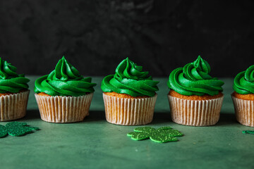 Obraz na płótnie Canvas Tasty cupcakes for St. Patrick's Day on green table against black background