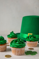 Obraz na płótnie Canvas Tasty cupcakes for St. Patrick's Day, leprechaun hat and coins on white background