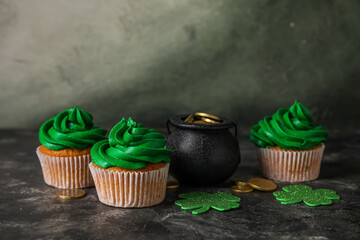 Obraz na płótnie Canvas Tasty cupcakes for St. Patrick's Day and pot of coins on black grunge table