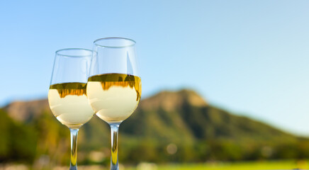 Pair of wine glasses against a beautiful tropical Diamond head in Hawaii mountain background. Dream summer romantic honeymoon vacation Hawaii concept. 
