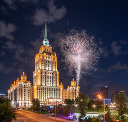 Fototapeta na wymiar Illuminated high-rise stalinist building at summer night and fireworks in the night sky in Moscow , Russia. Historic name is Hotel Ukraina.