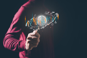 business and technology concept, man holding magnifying glass with virtual glob internet network and currency or stock trading graph, invesment online global economy