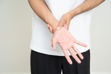 Obraz premium Close up man has an inflamed wrist because he is overworked. Massaged his wrists to soothe and relax. Shot on isolated white background.