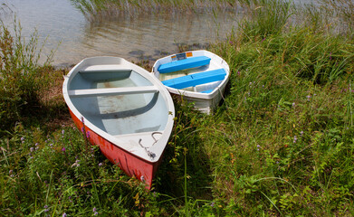 two rowboat anchored on the shore of a lake