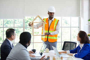 male African engineer meeting with colleague, showing wooden house model and presentations work in the office