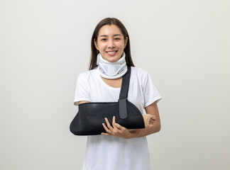 Happy young asian woman broken arm on isolated background. Asian female put on plaster bandage cast...