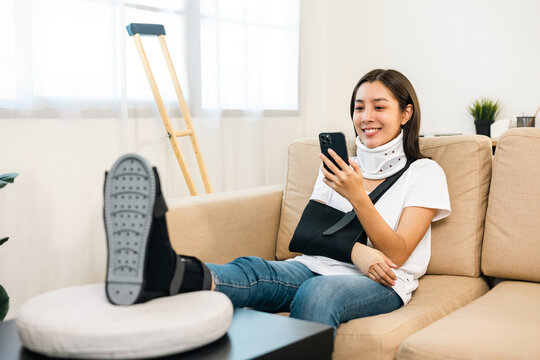 Woman recovery from accident fracture broken bone injury with leg splints in cast neck splints collar arm splints sling support arm using smartphone. Social security and health insurance concept.