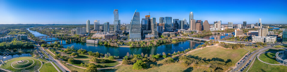 Panoramic view of Colorado River and Austin Texas cityscape. There is a view of a park at the front and bridges over the river near the skyscrapers. - Powered by Adobe