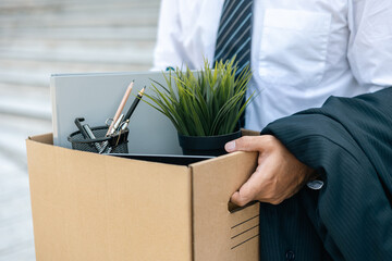 Businessman with box cardboard packing personal items after losing jobs. Failure businessman standing at front of building. Your fired Unemployed Jobless People Crisis - obrazy, fototapety, plakaty