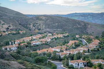 Fototapeta na wymiar View of a residential area on a slope from a hiking trail at San Clemente, California. Subdivision on a mountain with a view of sky at the background.