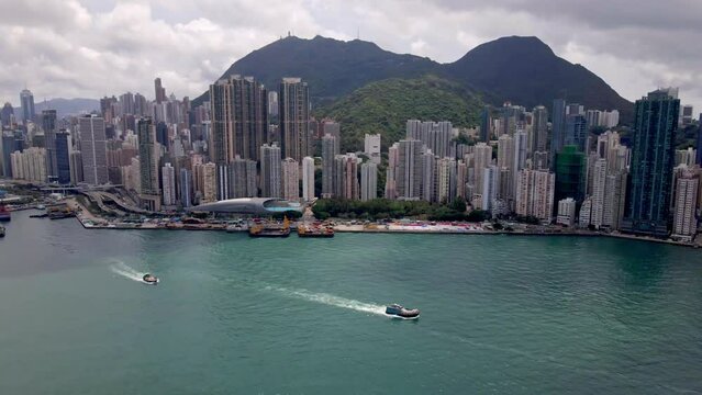 Kennedy Town in Hong Kong. Aerial view of the harbour. Boats in the water with ferries. Mountains and Peak in the background. Popular tourism destination in Asia. Skyscrapers. 