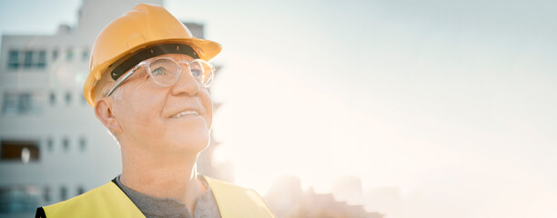 Senior man, builder and construction in the city with smile and helmet for safety or security at site on mockup. Elderly male contractor, engineer or technician face smiling with hard hat in town - obrazy, fototapety, plakaty