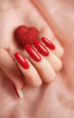 Girl's hands with red manicure and decoratine heart