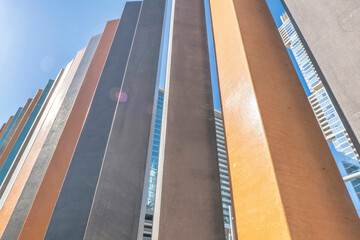 Low angle view of orange and gray concrete columns- Austin, Texas. Row of concrete pillars with views of high rise buildings in between the gaps. - Powered by Adobe