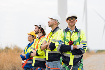 Portrait of group male and female engineers wear safety uniform and equipment preparing plan inspecting or maintenance of wind turbines at wind farm. Team of engineers working at wind turbines farm