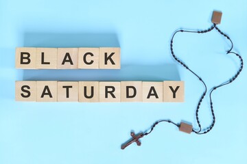 Black Saturday holy week concept. Wooden blocks typography with rosary flat lay in blue background. - Powered by Adobe