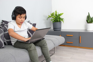 9-year-old Hispanic boy plays video games on his laptop with headphones leading to being overweight and poor sitting posture