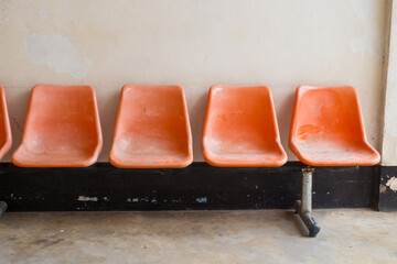 Orange plastic chairs at the bus stop.