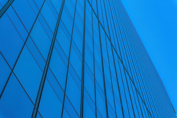 Frameless glass facade of a building at Austin, Texas downtown. Low angle view of a building with reflection of blue sky on its glass exterior.