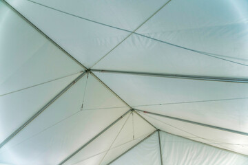 Metal frames of a white tent canopy at San Antonio, Texas. Inside a tent canopy with steel frames against white fabric top in a low angle view.