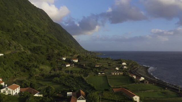rural coastal village and crop fields in lush green cliffs, Faj&atilde; dos Vimes, S&atilde;o Jorge island, the Azores, Portugal