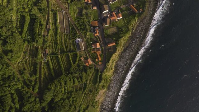 top-down view of a rural coastal village with crop fields, Lush green cliffs landscape over the Atlantic, Faj&atilde; dos Vimes, S&atilde;o Jorge island, the Azores, Portugal