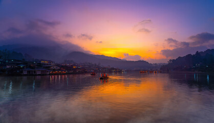 Tourists take a boat with mist fog over lake in morning at Ban Rak Thai village in Mae Hong  Son province, Thailand.