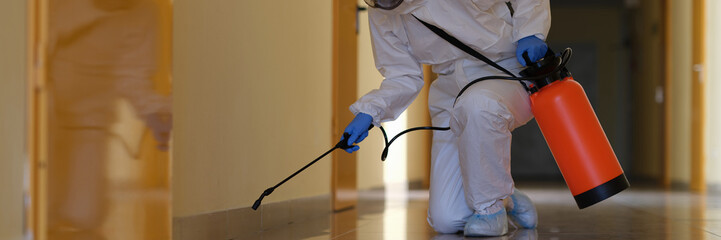 Person in protective suit disinfects office and corridors to prevent spread of COVID-19