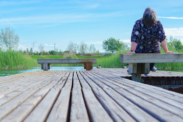 woman sitting on a bench on a lake pontoon looking up at the sky
