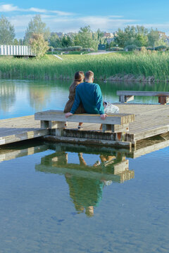 young couple sitting on the bench of a lake pontoon