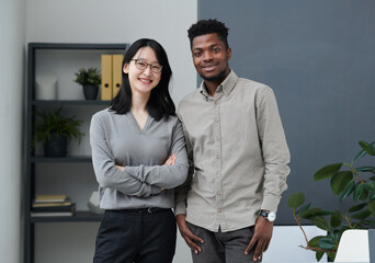 Portrait of multiethnic business couple smiling at camera while standing in office and working together