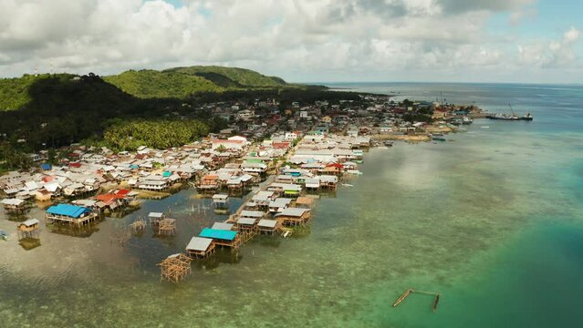 Fishing village with boats and slums with wooden houses, aerial drone. Dapa, Siargao, Philippines.