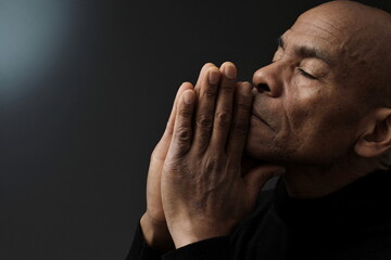 man praying to god with grey black background with people stock photo