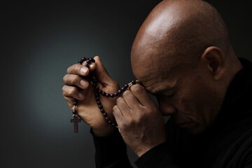 Naklejka na ściany i meble man praying to god with grey black background with people stock photo