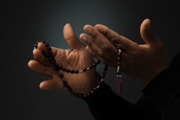 man praying to god with cross and hands together with black background with people stock photo   