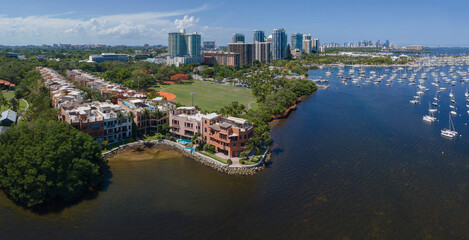 Fototapeta na wymiar Coconut Grove Sailing Club in Miami Florida with buildings and ocean scenery. Aerial view of the coastal landscape with white sailing boats floating in the sea.