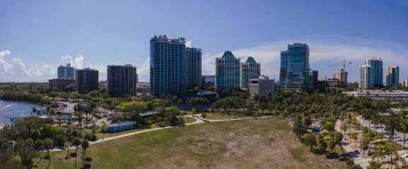 Panorama of beautiful Miami Florida city skyline on a bright sunny day. Modern buildings, partial view of ocean, and wide green lawn can be seen in this scenic landscape.