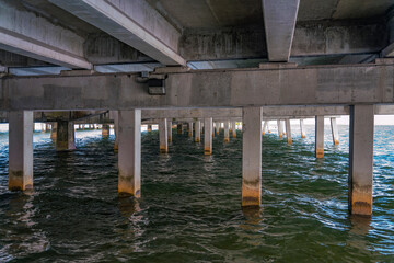 Underneath a concrete bridge over the water at Rickenbacker Causeway in Miami, Florida. Views of bridge support pillars with dried algae marks.