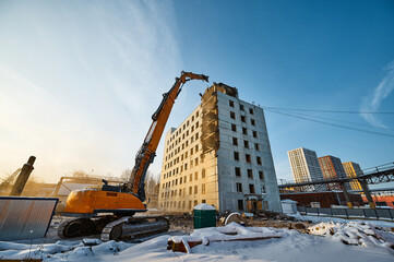 Fototapeta premium Dismantling of old highrise building with crawler excavator