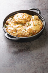 Creamy smothered pork chops seared and cooked in a rich onion gravy closeup on the pan on the table. Vertical
