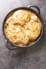 Southern classic comfort food, crispy coated pork chops smothered in a rich onion gravy closeup on the pan on the table. Vertical top view from above
