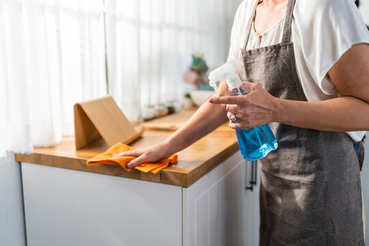 Caucasian senior elderly woman wearing apron, cleaning kitchen at home. 