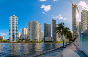 Miami, Florida cityscape views from Miami River Walk. There is a concrete walkway with wall on the...
