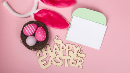 colored easter eggs and rabbit ears and envelope and blank for text on pink background easter minimal flat lay top view